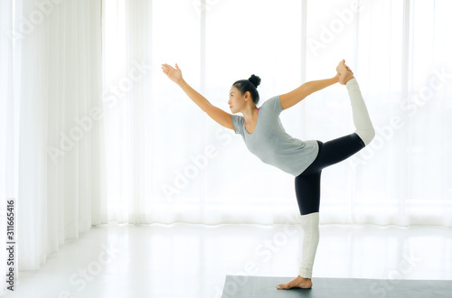 Side view of Beautiful Asian woman practicing yoga, standing in Natarajasana exercise, Lord of the Dance pose, working out, wearing sportswear,full length,indoor,lifestyle healthy concept. photo