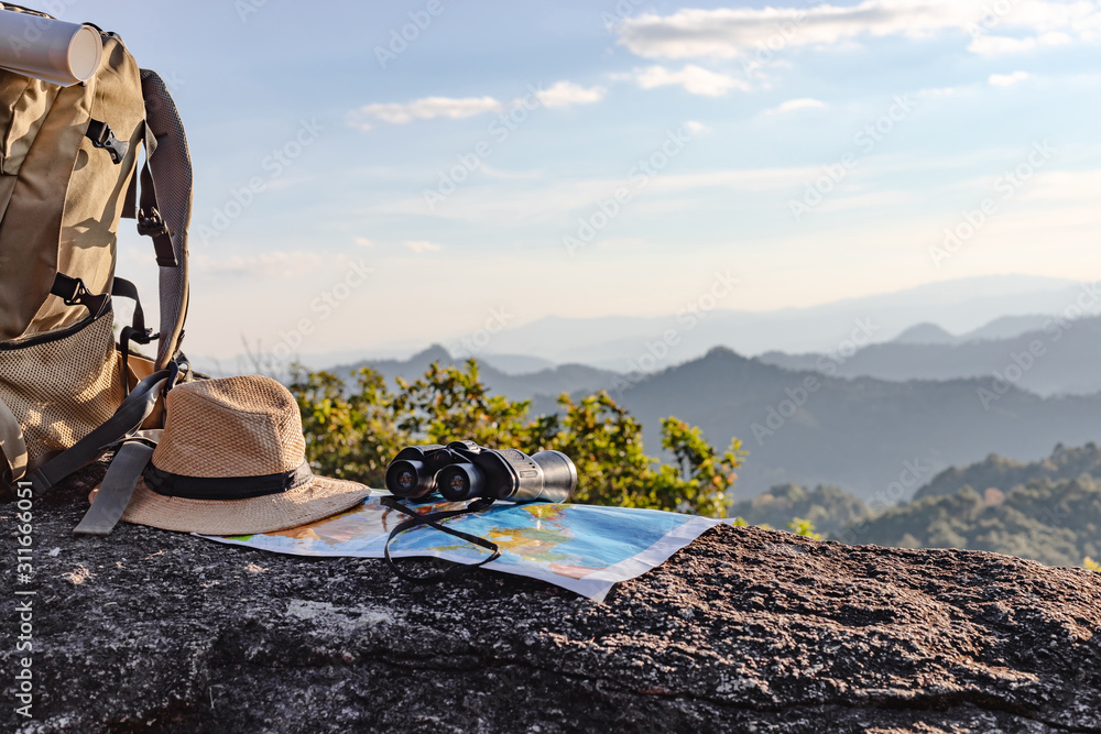 binoculars and map and hat and backpack on the rock mountains. - obrazy, fototapety, plakaty 