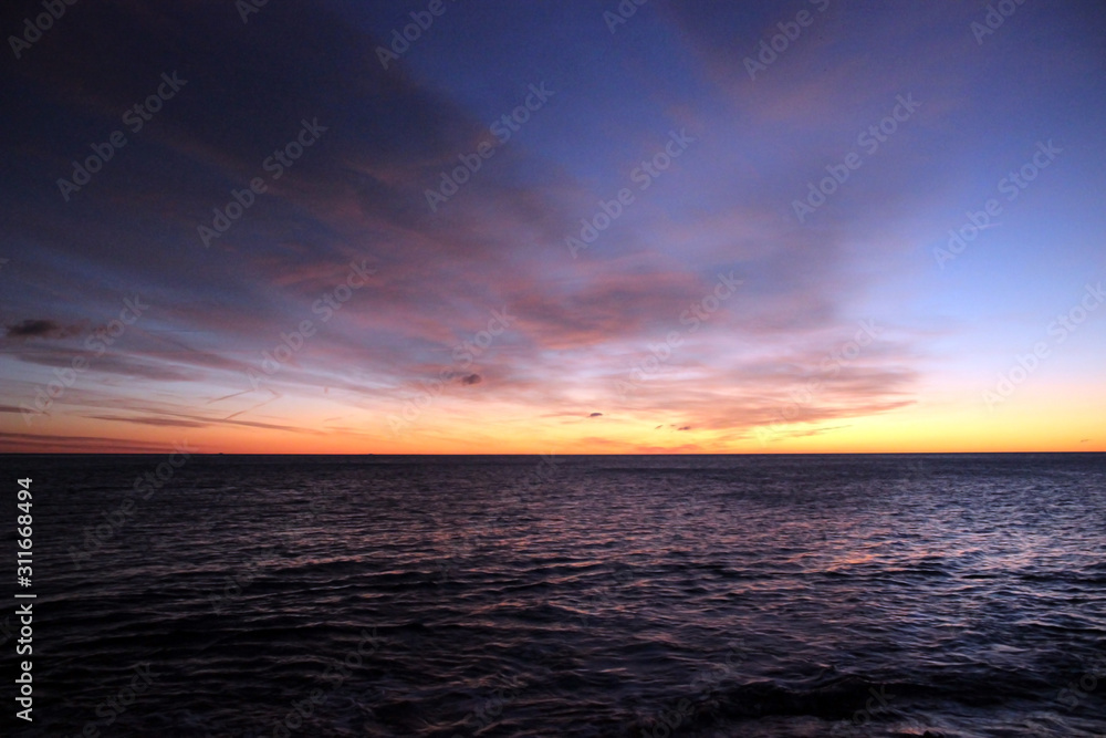 Sunrise at the sea with blue cloudy sky