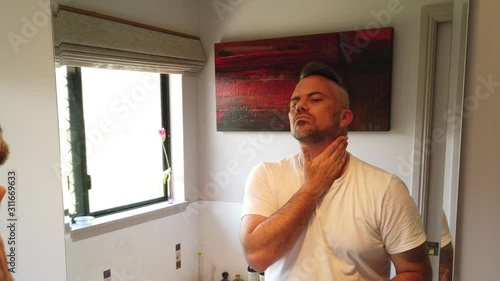 man putting the finishing touches on his beard, morning shave. getting ready for the day and having a shave in the mirror photo