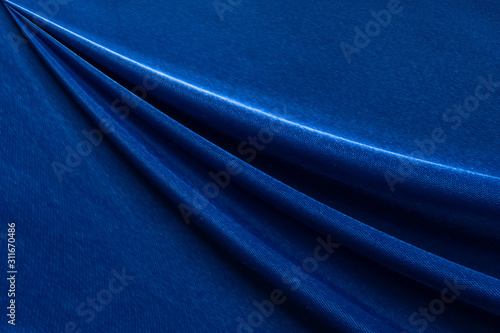 Luxury deep blue fabric background.Smooth wavy fold pattern.Elegant curve.Silk velvet material texture.Using for backdrop or wallpaper.Dark tone color.
