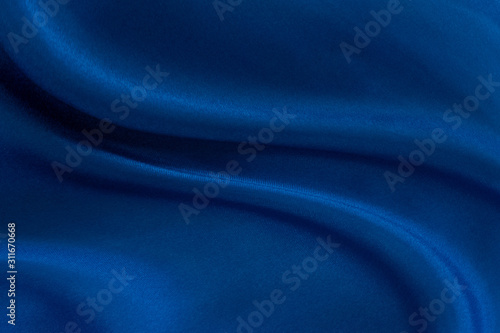 Luxury deep blue fabric background.Smooth wavy fold pattern.Elegant curve.Silk velvet material texture.Using for backdrop or wallpaper.Dark tone color.