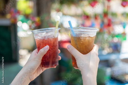 Hand 's people holding two plastic glass of cold sparkling or carbonated water with colorful blured background. 