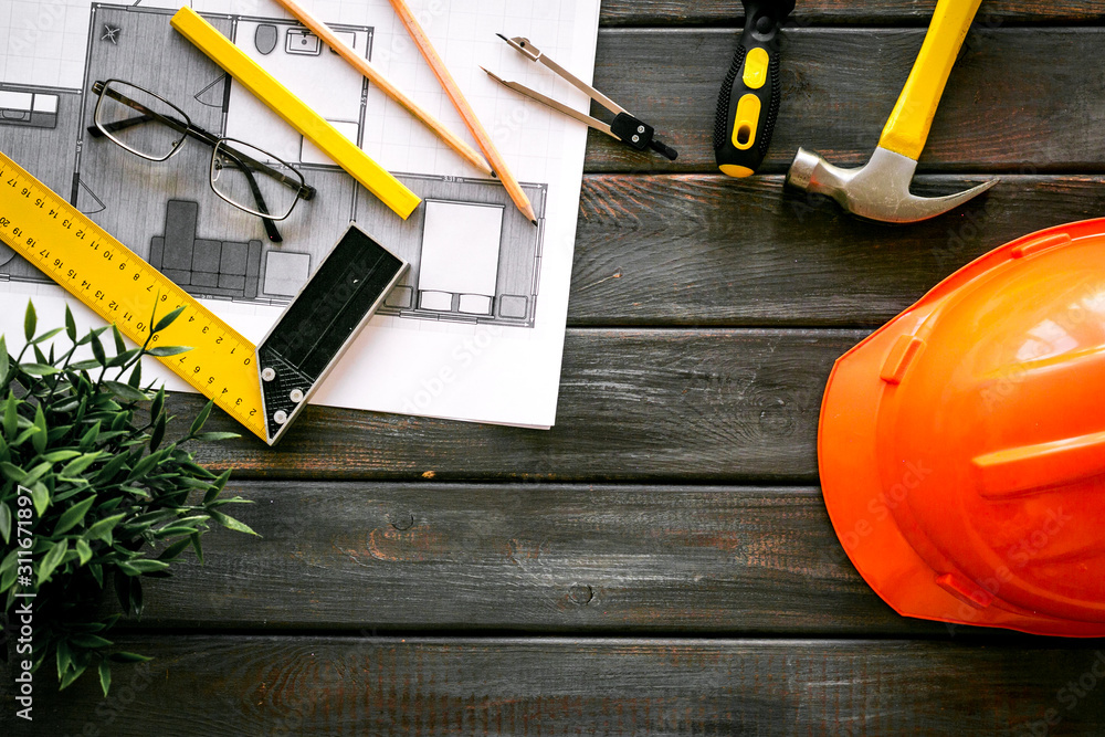 Builder work desk with hard hat, instruments and blueprints on dark wooden background top-down frame copy space Builder work desk with hard hat, instruments and blueprints on dark wooden background top-down frame copy space