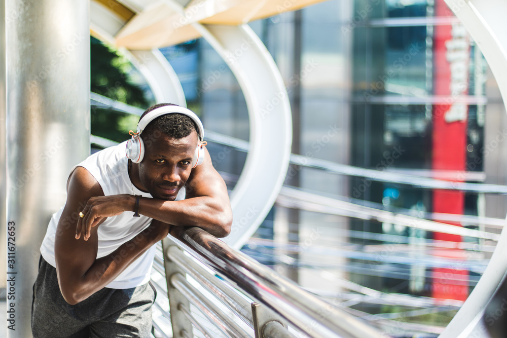 Portrait of a young African man wearing a white headphones He is relaxing by listening to music. Holiday and relaxation concepts. cinematic tone