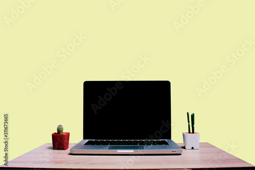 laptop and cup of coffee on wooden table on isolate pastel yeloow background