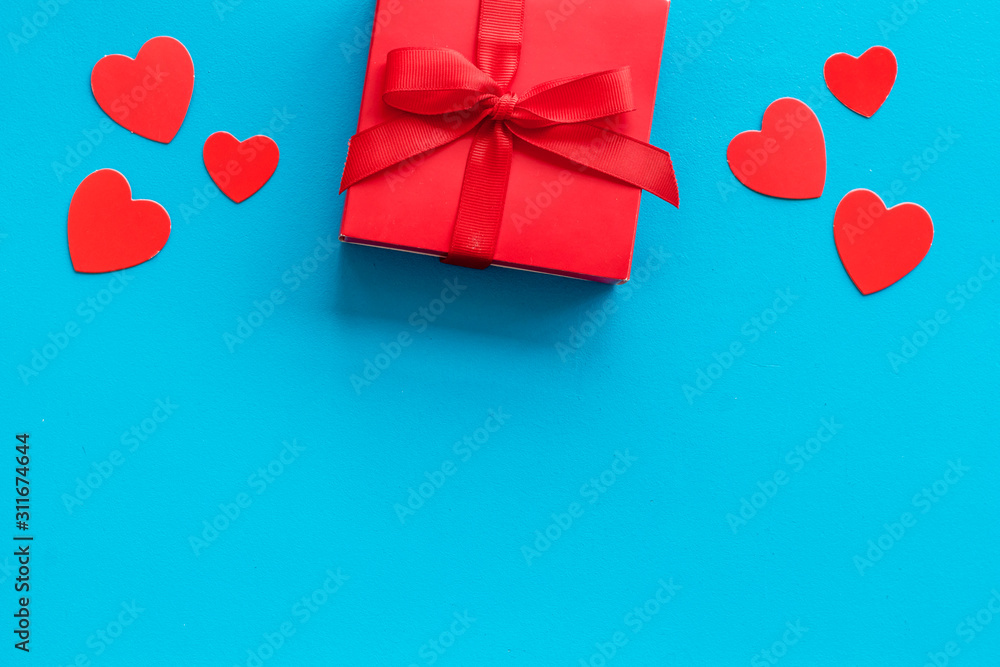 Gift to a sweetheart on Valentine's Day. Red present box near hearts on blue background top-down copy space