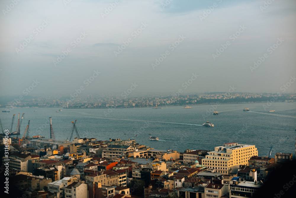 Top view on the roofs of Istanbul Turkey houses against the backdrop of the Bosphorus with ferry cargo cranes at sunset.