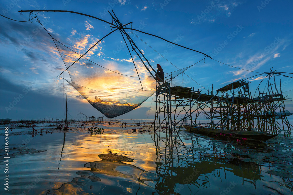 A view of the lake in the morning at Pakpra, Phattalung, Thailand and the fisherman's way of life catching fish using a large net.