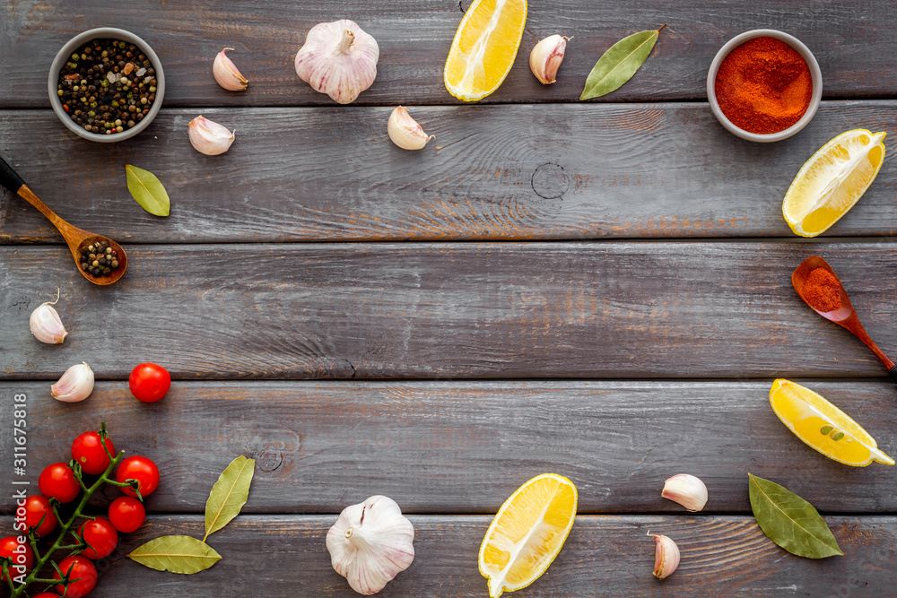 Kitchen frame with spices and food - pepper, garlic, tomatoes - on dark wooden background top-down frame copy space
