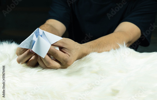 The man's hand is holding a paper that predicts the fate known as Paper Fortune Tellers. To predict the future, work, love, fate, sometimes used as a fun game to play. There is space for copy space.