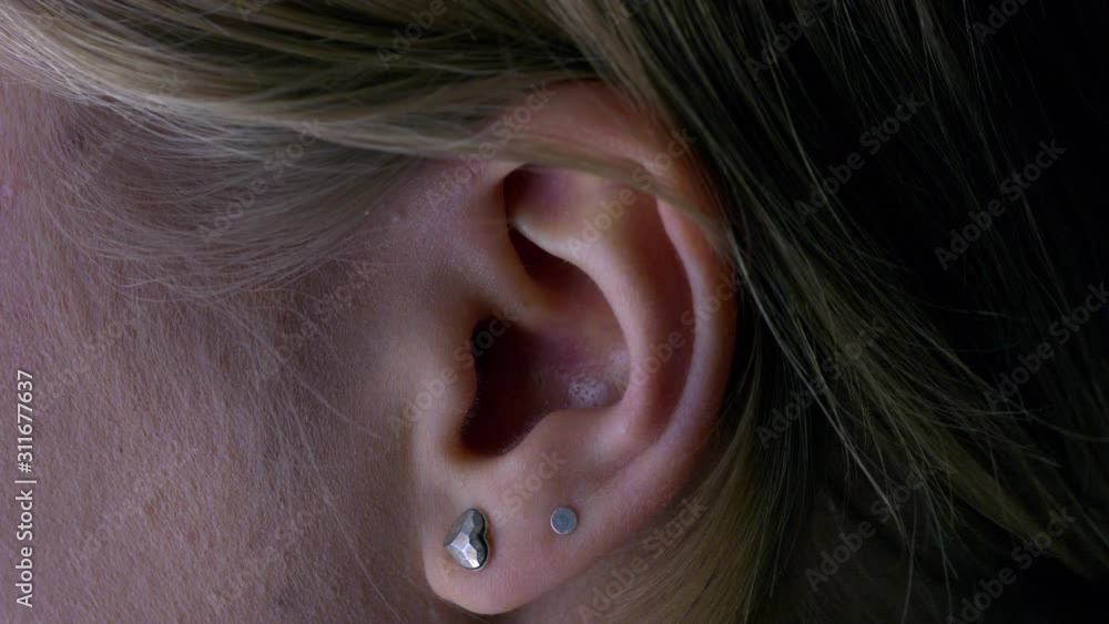 Close-up macro of the ear of a young woman with two earrings. Hearing and ear care concept. Close-up macro of the ear of a young woman with two earrings. Hearing and ear care concept.
