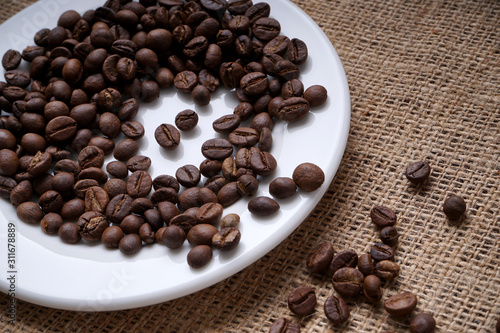 Coffee beans on white plate and fall on jute 