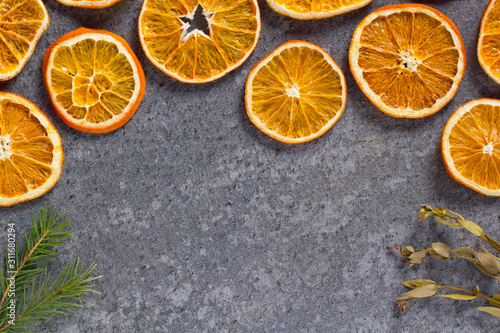 Fototapeta Naklejka Na Ścianę i Meble -  Christmas background mockup top view with copy space. Fir tree branches and dry oranges on dark background flat lay. Winter holiday frame. New Year's composition. Mockup sliced oranges with a crust.