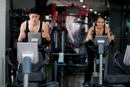 Attractive Woman and man is Workout Cycling Exercise in Fitness Gym., Portrait of Pretty Caucasian Woman is Cycling Training in Gym., Sport Club and Healthy Concept.