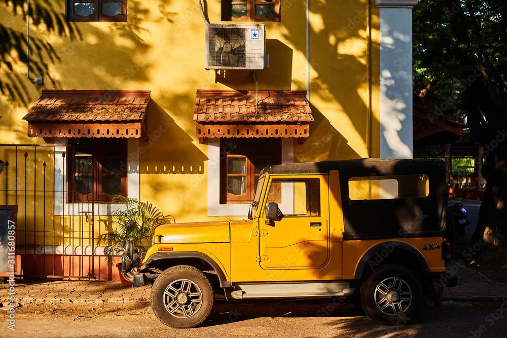 Panaji, Goa, India - December 15, 2019: Yellow House. The car is parked near the house. Streets of the state capital GOA Panaji