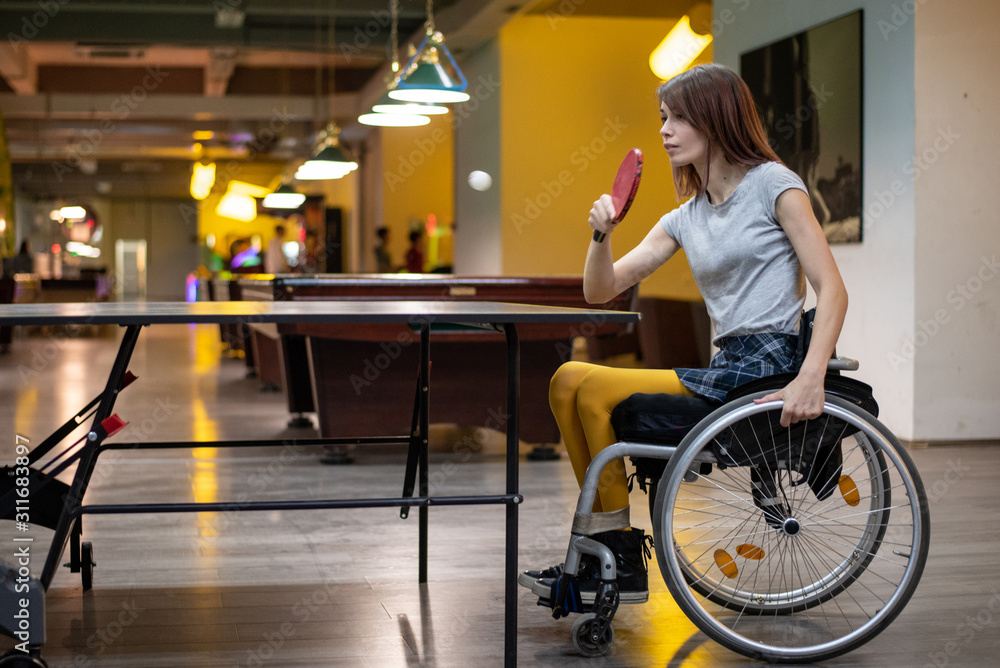 Young disabled woman in a wheelchair playing table tennis Young disabled woman in a wheelchair playing table tennis