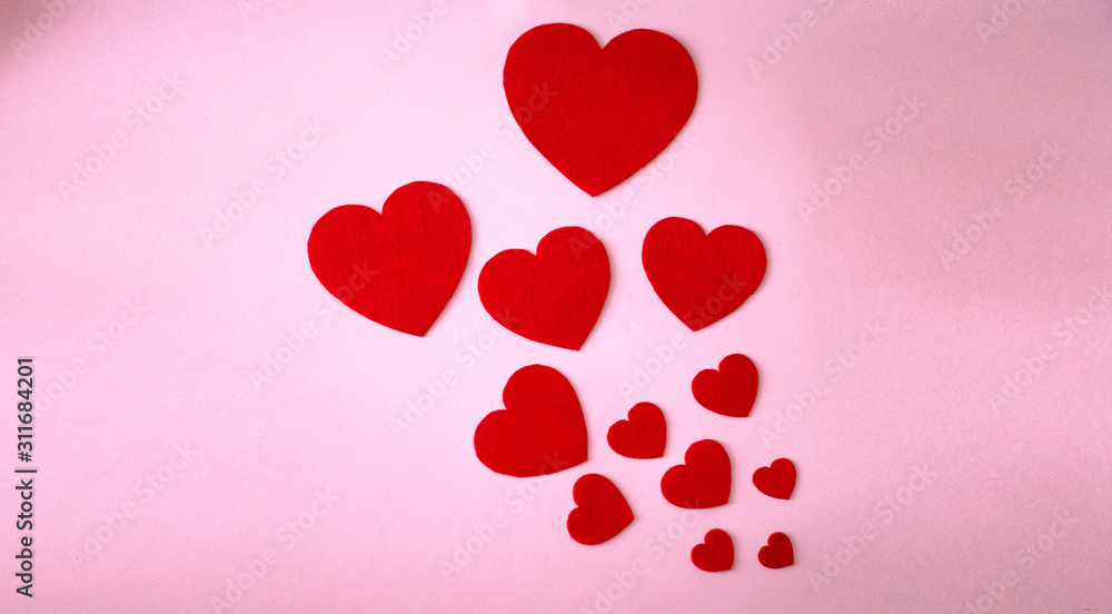 Paper hearts on a pink background. Twelve paper hearts of different sizes.