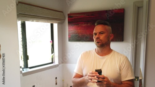 man having his morning shave in the mirror using an electric razor in slow motion, daily routine, grooming in the morning photo