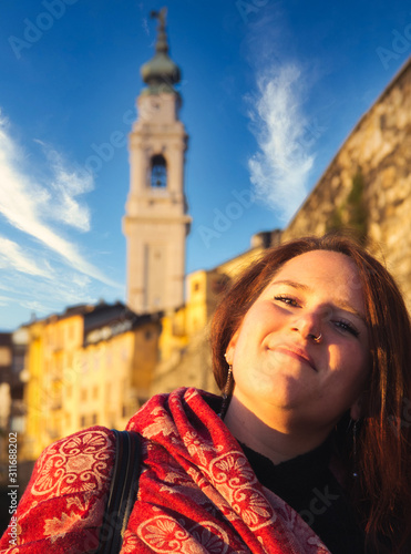 Portrait of a chubby smiling girl with bell tower background during winter sunset