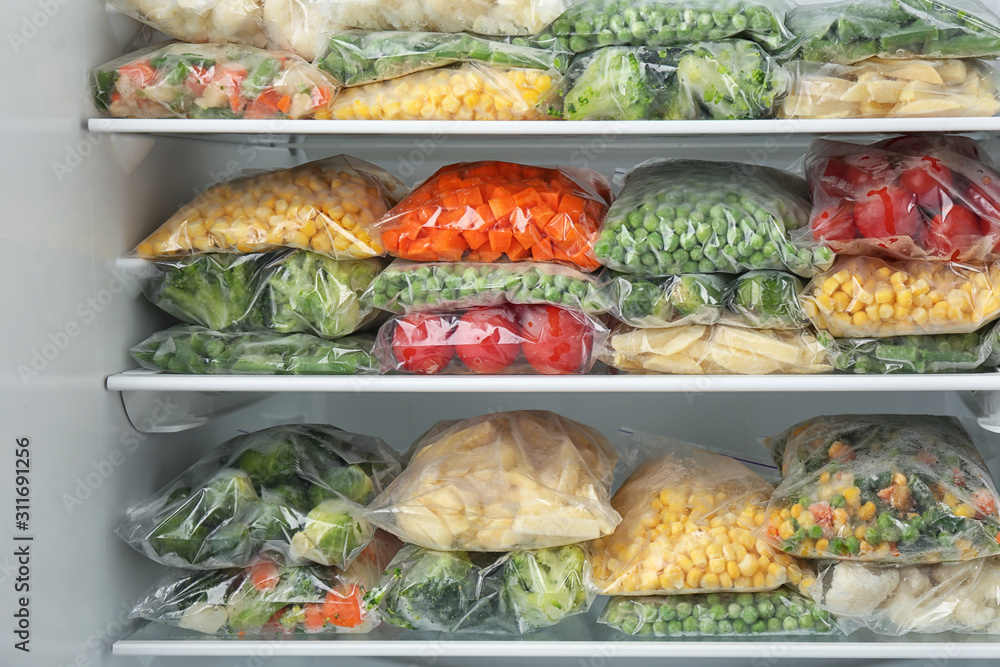 Plastic bags with different frozen vegetables in refrigerator Stock