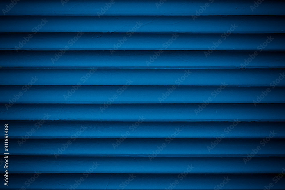 Dark blue metallic striped surface. Metal wall siding. Striated fence with shine. Convex wall texture. Ribbed surface of metal jalousie, door. Abstract pattern from lines. Dark blue metallic striped surface. Metal wall siding. Striated fence with shine. Convex wall texture. Ribbed surface of metal jalousie, door. Abstract pattern from lines.