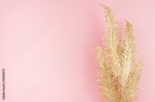 Modern stylish golden festive background - golden glittering palm branch on soft light pastel pink background  top view  copy space.