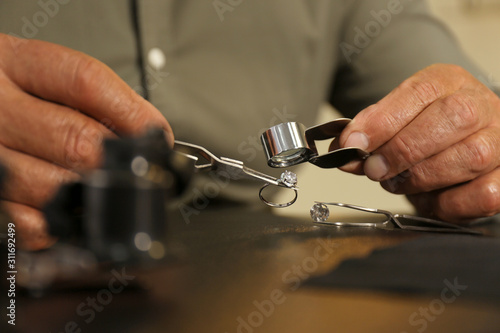 Professional jeweler working with beautiful ring at table, closeup