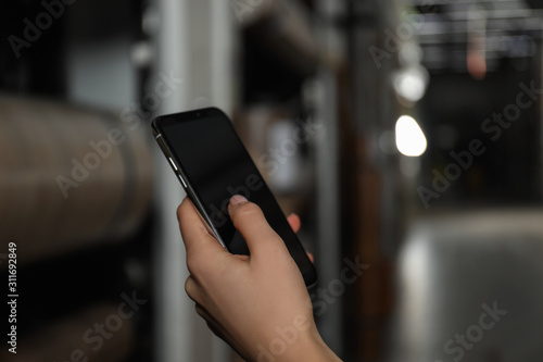 Woman with smartphone in wholesale warehouse, closeup. Space for design