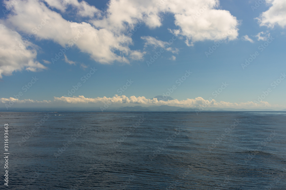 The endless clear blue sea and the blue sky with white clouds merge on the horizon. Seascape. Natural background The endless clear blue sea and the blue sky with white clouds merge on the horizon. Seascape. Natural background