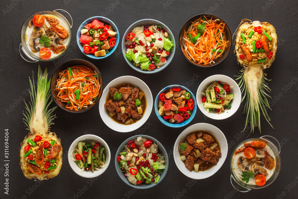 Assortment of Thai cooked dishes in bowls on a black concrete background. Top view. Assortment of Thai cooked dishes in bowls on a black concrete background. Top view.