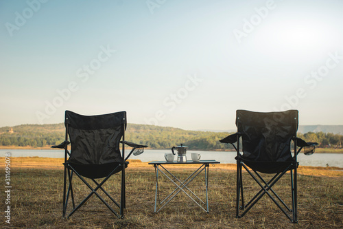 Outdoor two empty chairs with picnic table and moka pot coffee for Camping. © ME Image