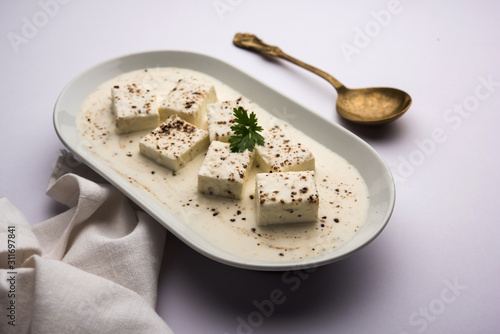 Paneer Dum Kali Mirch / Kalimirch, prepared in a white creamy gravy and black pepper powder sprinkled over it. served in a bowl. Selective focus photo