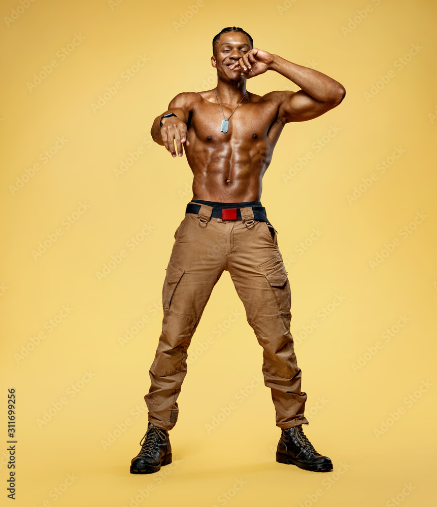 Muscular man shirtless. Photo of smiling man with perfect body after training on yellow background. Strength and motivation. Full length Muscular man shirtless. Photo of smiling man with perfect body after training on yellow background. Strength and motivation. Full length