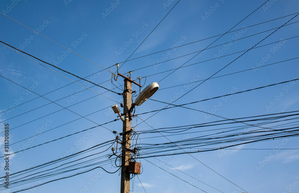 old post with a lantern and power wires. many wires and the pole that connects them. wiring technologies in eastern Europe. old post with a lantern and power wires. many wires and the pole that connects them. wiring technologies in eastern Europe.