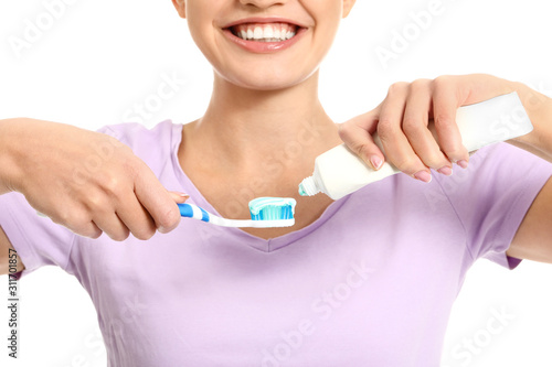 Young woman with toothbrush and paste on white background