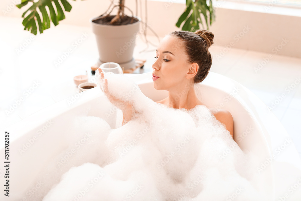 Naklejka premium Beautiful young woman relaxing in bathtub