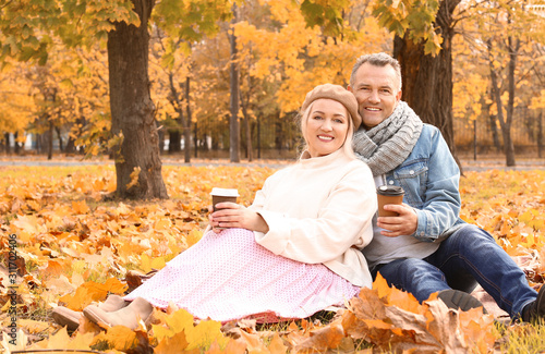 Happy mature couple drinking coffee in autumn park