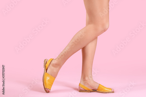 Legs of young woman in stylish shoes on color background