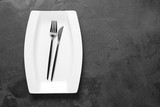 Empty plate and cutlery on dark background