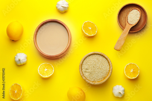 Bowl of tasty tahini, lemon and garlic on color background