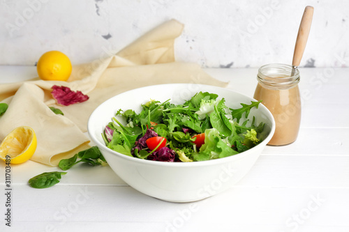 Fototapeta Bowl with vegetable salad and jar of tasty tahini on table