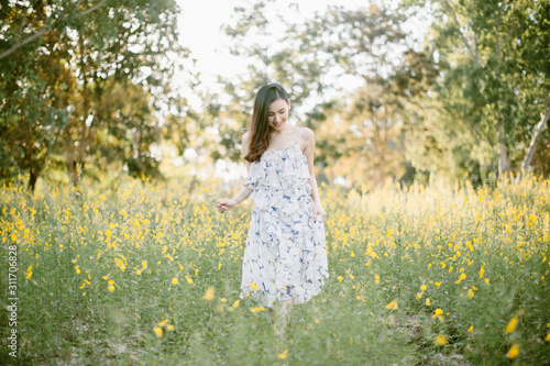 happy young woman enjoying summer in yellow flower field