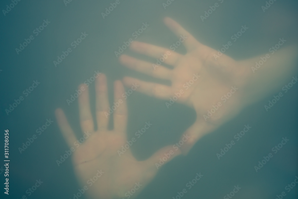 Obraz premium Hands behind the frosted glass. hands silhouette in the mist. loneliness concept. palm touches the glass window