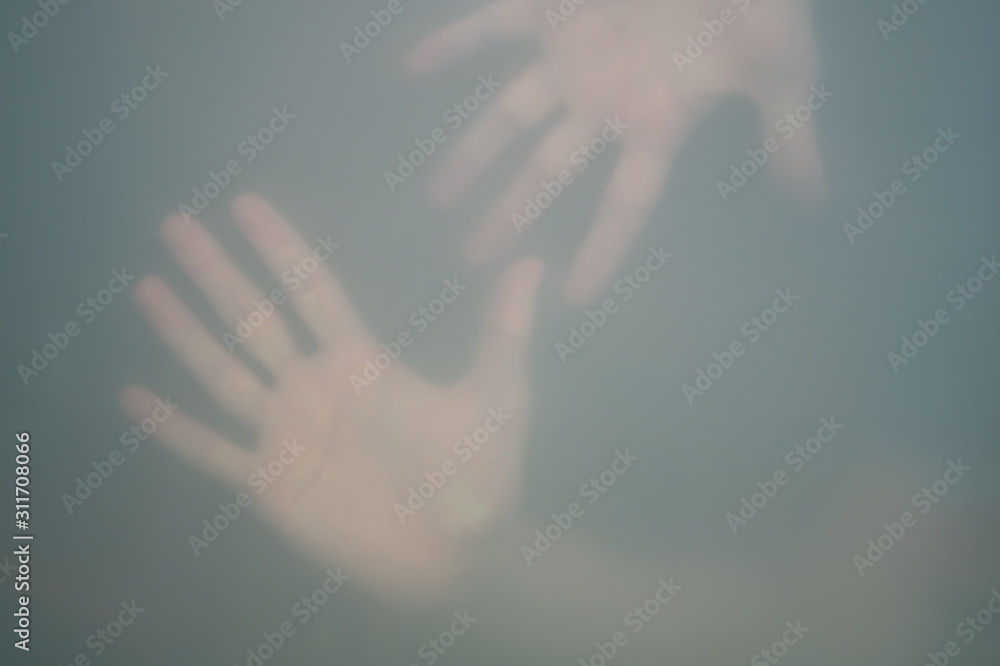 Hands behind the frosted glass. hands silhouette in the mist. loneliness concept. palm touches the glass window Hands behind the frosted glass. hands silhouette in the mist. loneliness concept. palm touches the glass window