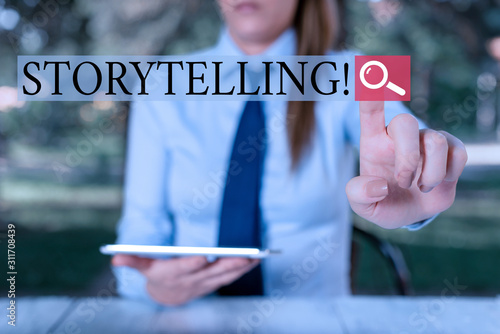 Text sign showing Storytelling. Business photo showcasing activity writing stories for publishing them to public Female business person sitting by table holding mobile phone