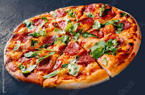 Pepperoni Pizza with Mozzarella cheese, salami, Tomato sauce, pepper, Spices and Fresh arugula. Italian pizza on Dark grey black slate background photo
