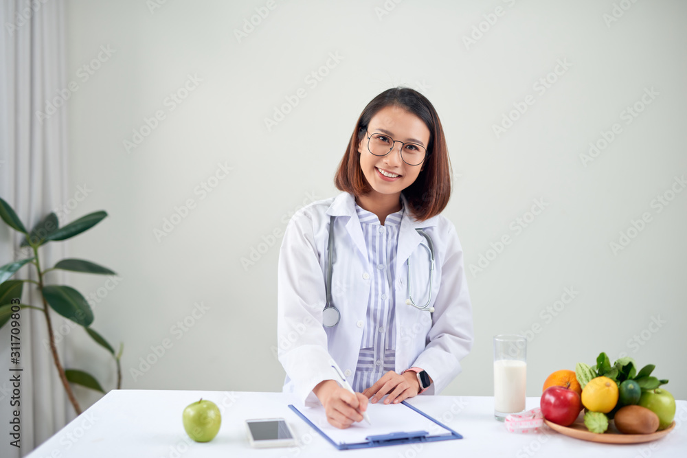 Asian Female nutritionist with fruits working at her desk. Health care and diet concept.
