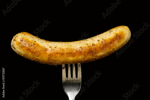 Delicious bratwurst sausage grilled with Italian mix herb on fork isolated on black background, Clipping path