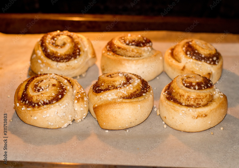 Cinnamon buns rolls on a tray lined with baking parchment paper in the oven